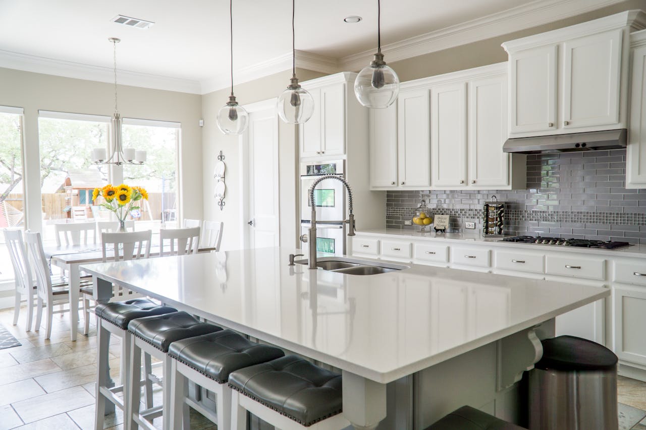 about-bg Spacious modern kitchen with white cabinets and island in natural light.